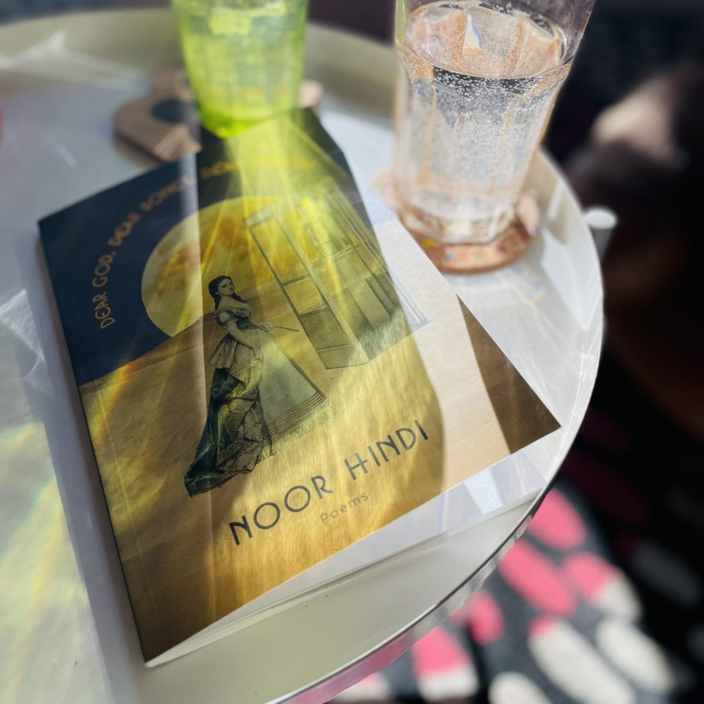 Poetry book by Noor Hindi in the sun rays on a white table.